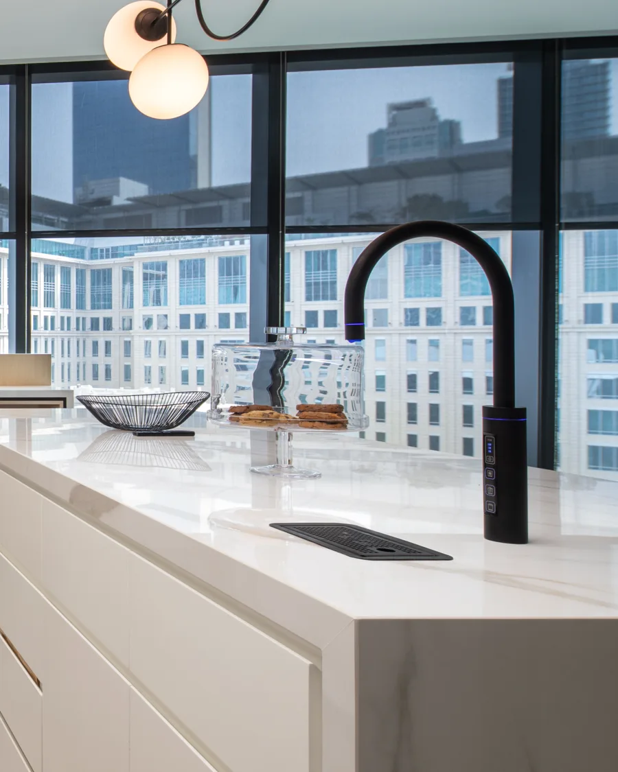 A Sprudel filtered-water tap on a marble kitchen island, overlooking a city skyline