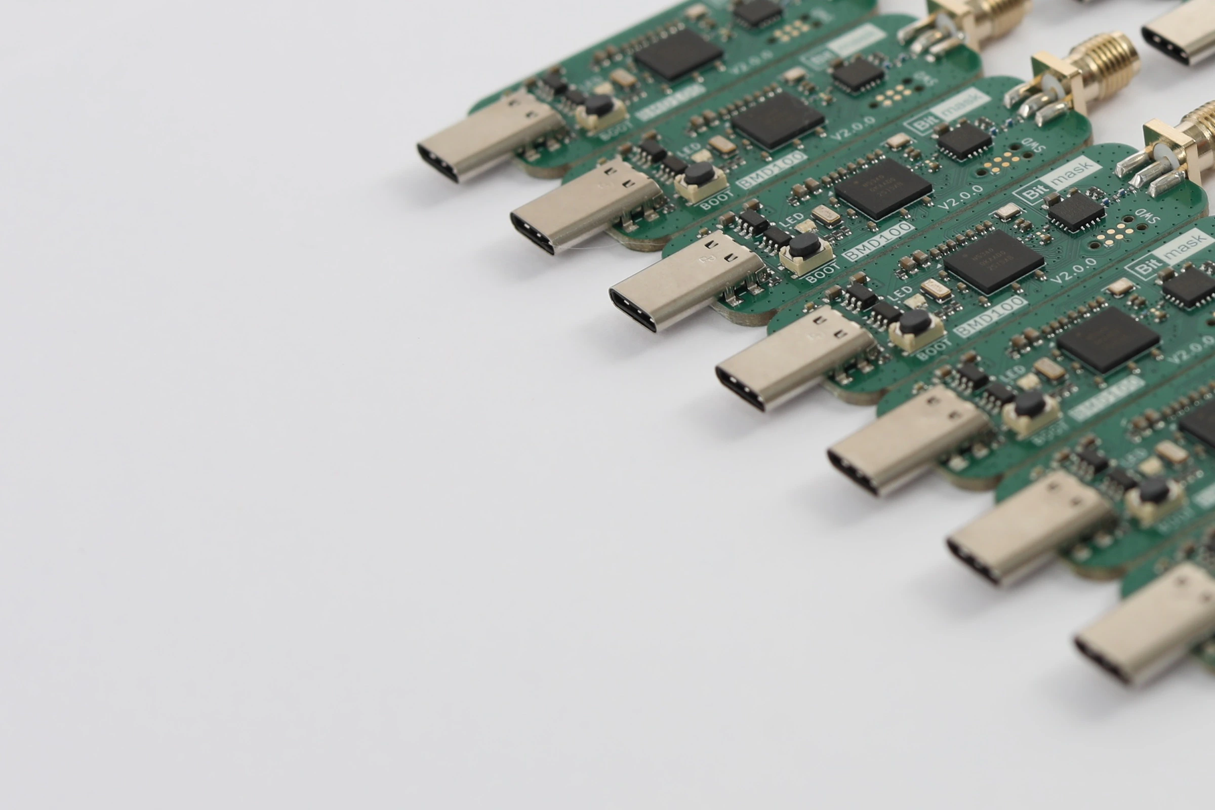Rows of Bitmask BMD100 dongles fanned out on a white bench, USB-C connectors facing forward