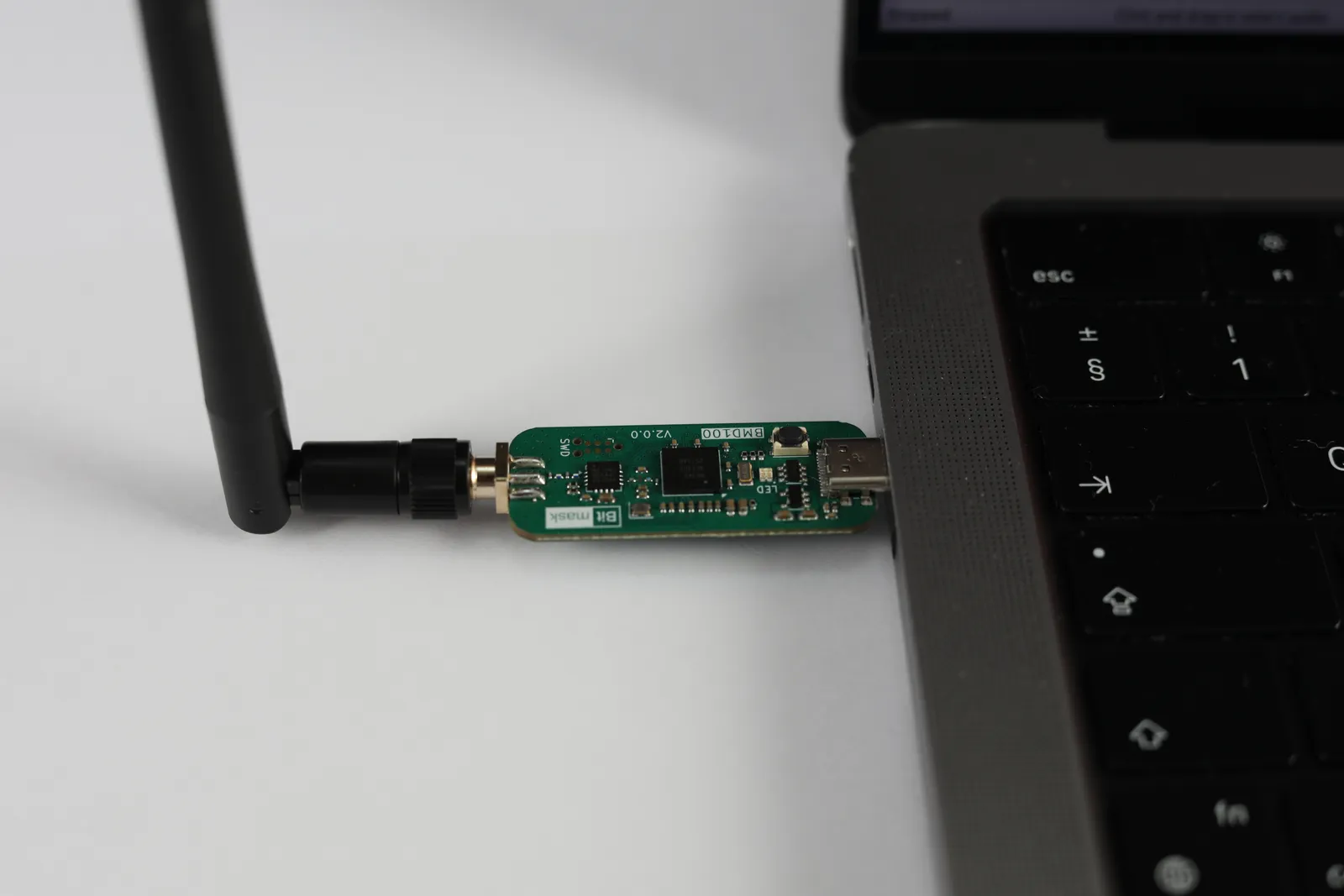 Close-up of a BMD100 board showing the USB-C connector, Nordic SoC, and Bitmask silkscreen, with the antenna attached