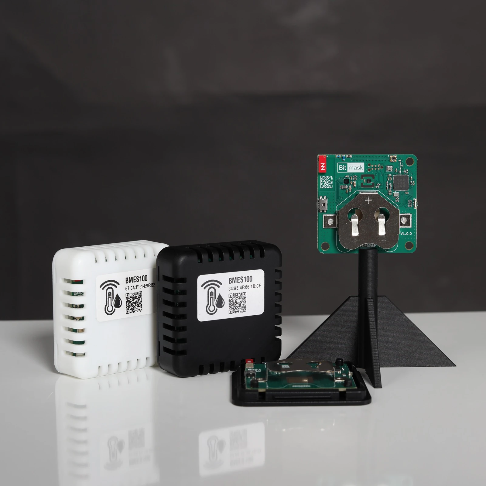 BMES100 sensors and a bare board on a stand, photographed against a dark studio background
